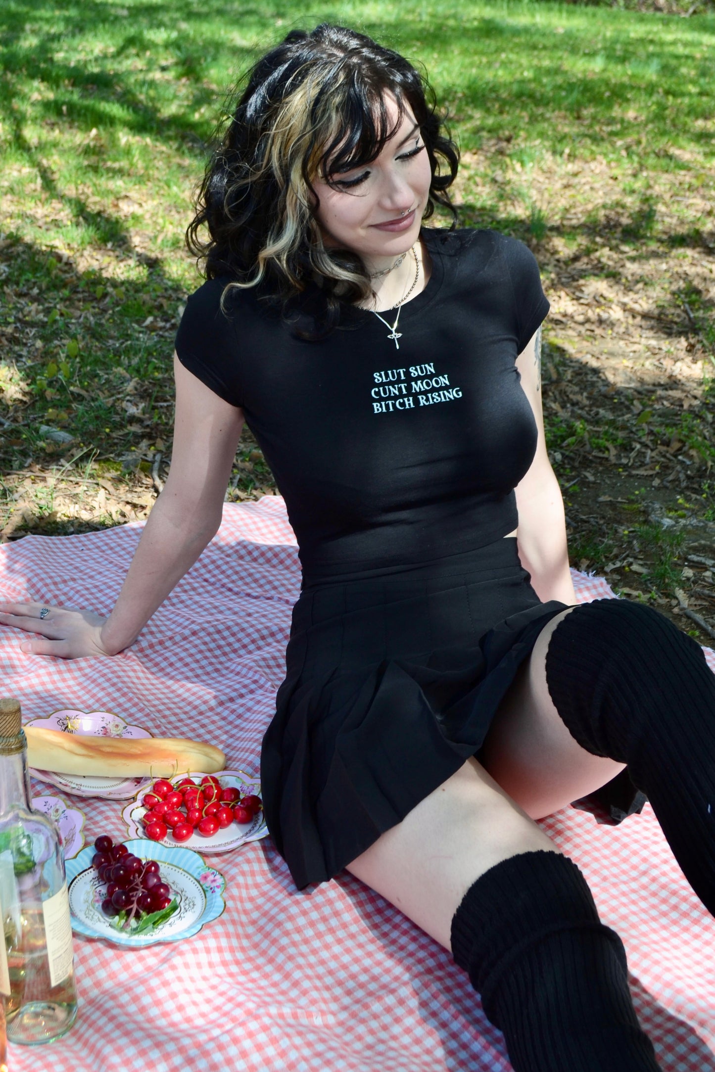 a woman sitting on a picnic blanket with a plate of food