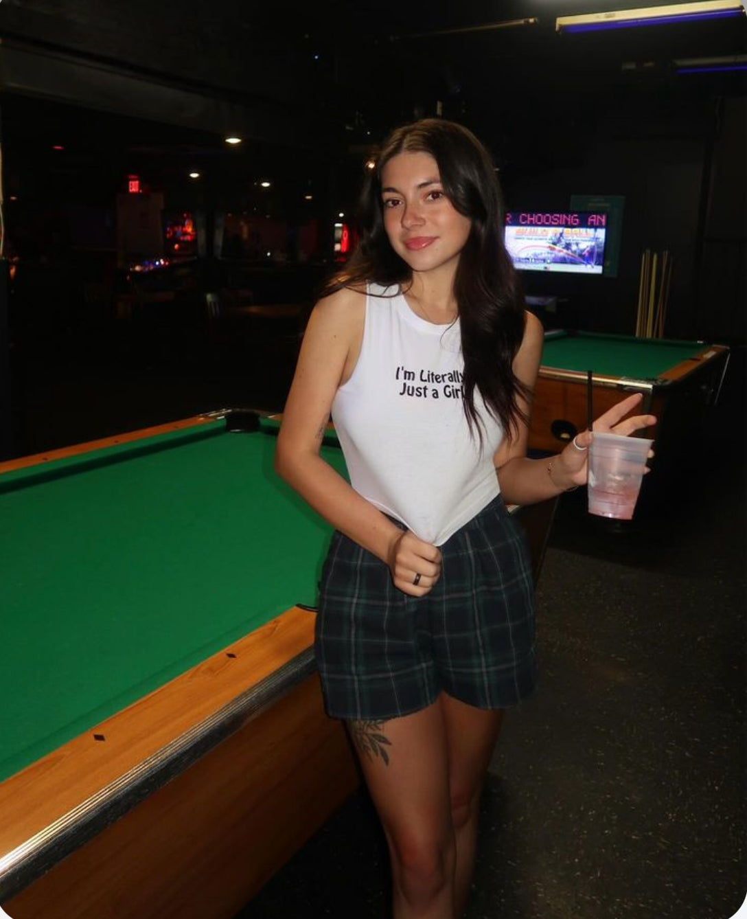 a woman standing next to a pool table holding a drink