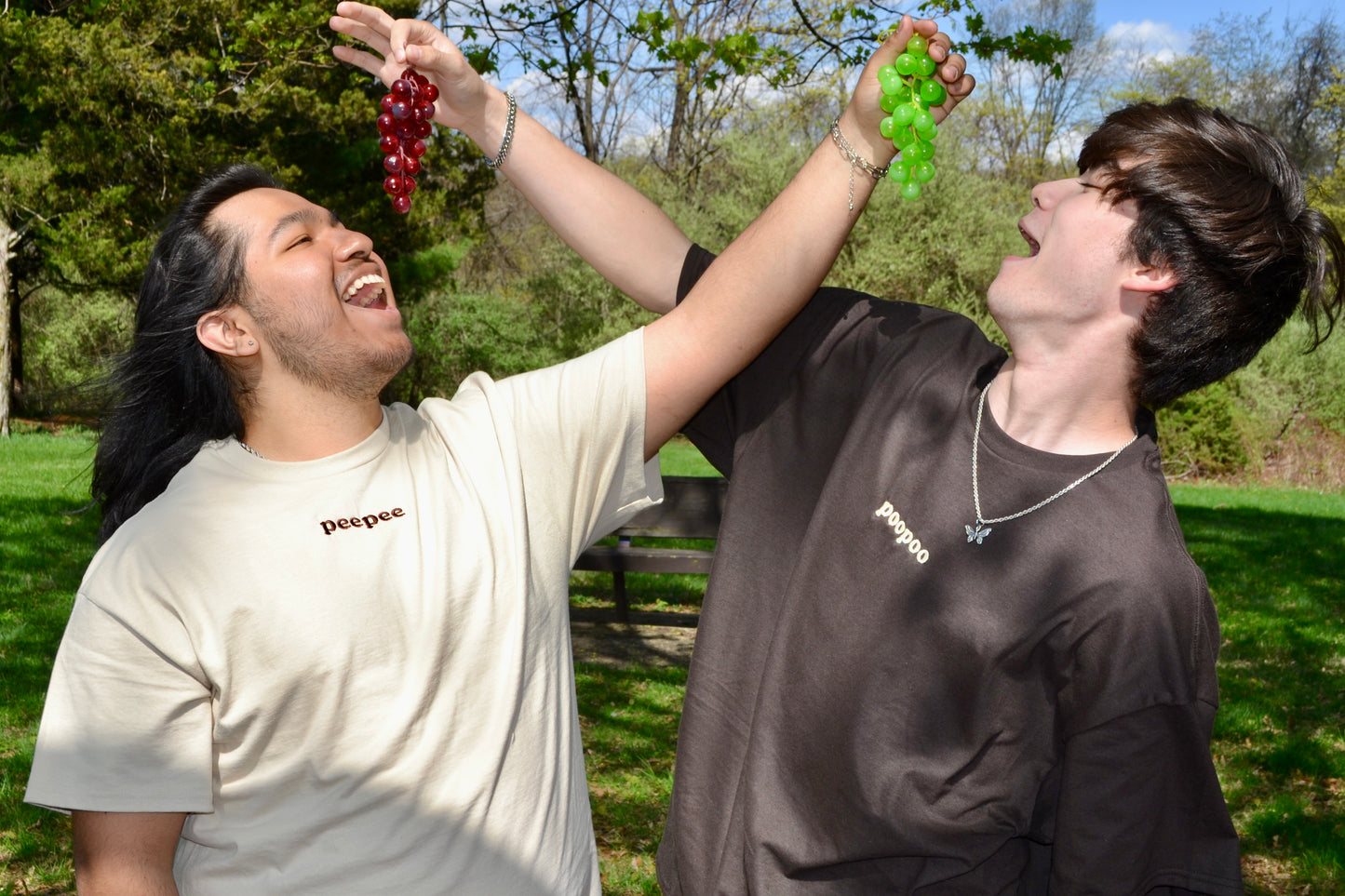 a man holding a bunch of grapes next to another man