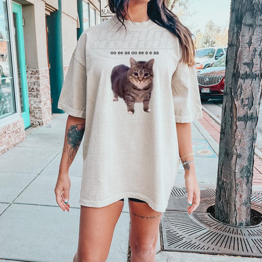 a woman standing on a sidewalk with a cat t - shirt on