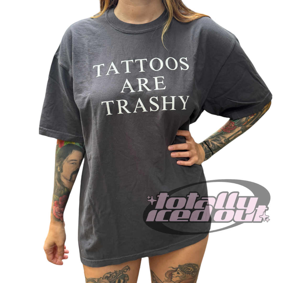 a woman wearing a tattoo t - shirt with the words tattoos are trashy on