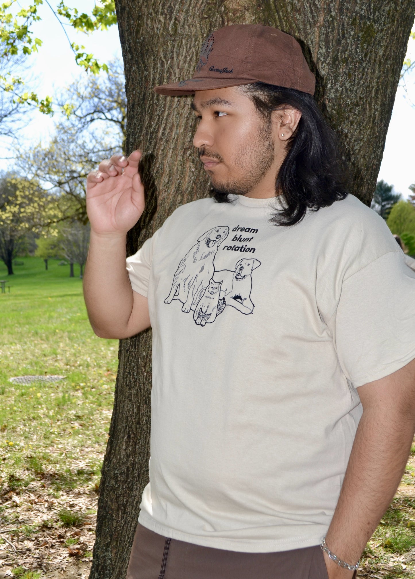 a man standing next to a tree wearing a hat