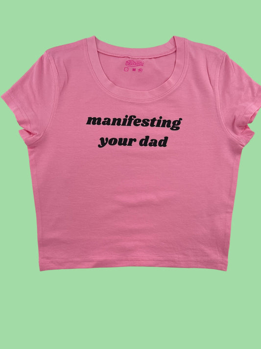 a pink crop top with the words manifisting your dad printed on it
