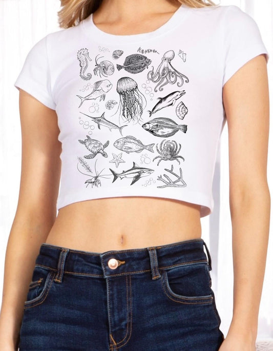 a woman wearing a white crop top with a drawing of sea animals on it