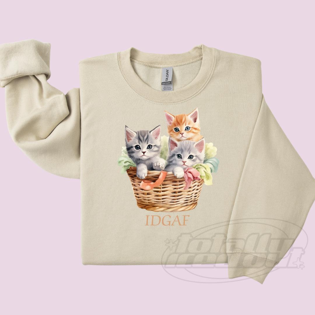 a sweater with a picture of three kittens in a basket