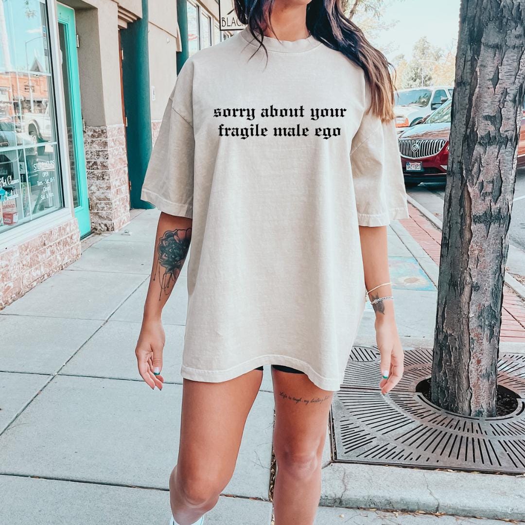 a woman standing on a sidewalk wearing a t - shirt