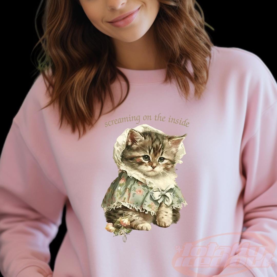 a woman wearing a pink sweatshirt with a cat on it