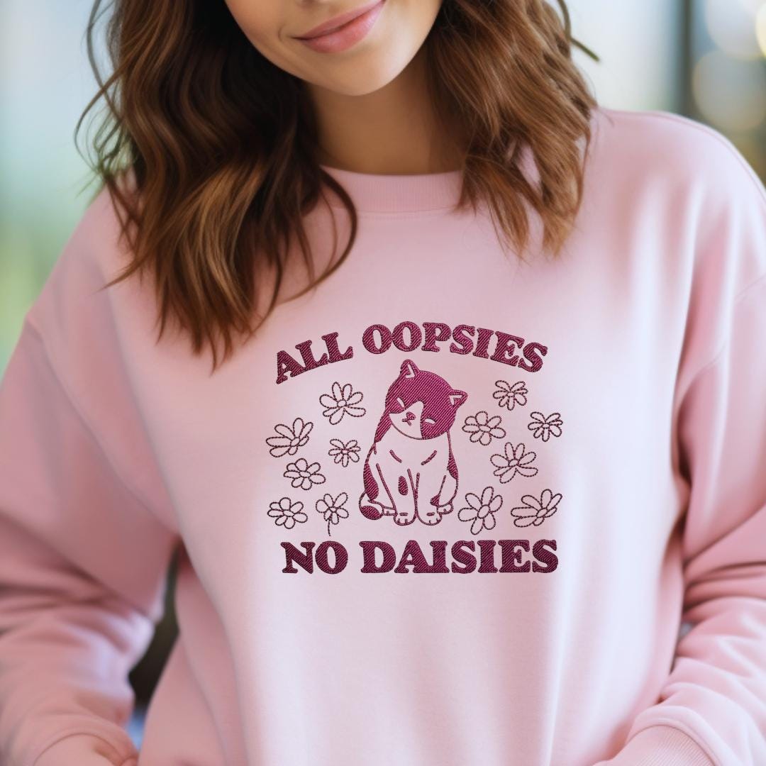 a woman wearing a pink sweatshirt that says all oppsies no daisies