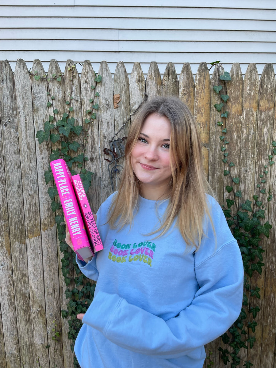 a girl in a blue sweatshirt holding a pink tube