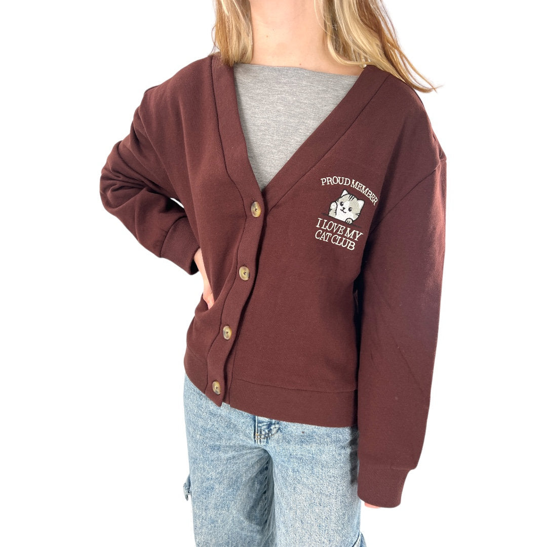 a woman wearing a brown cardigan with a white dog on it