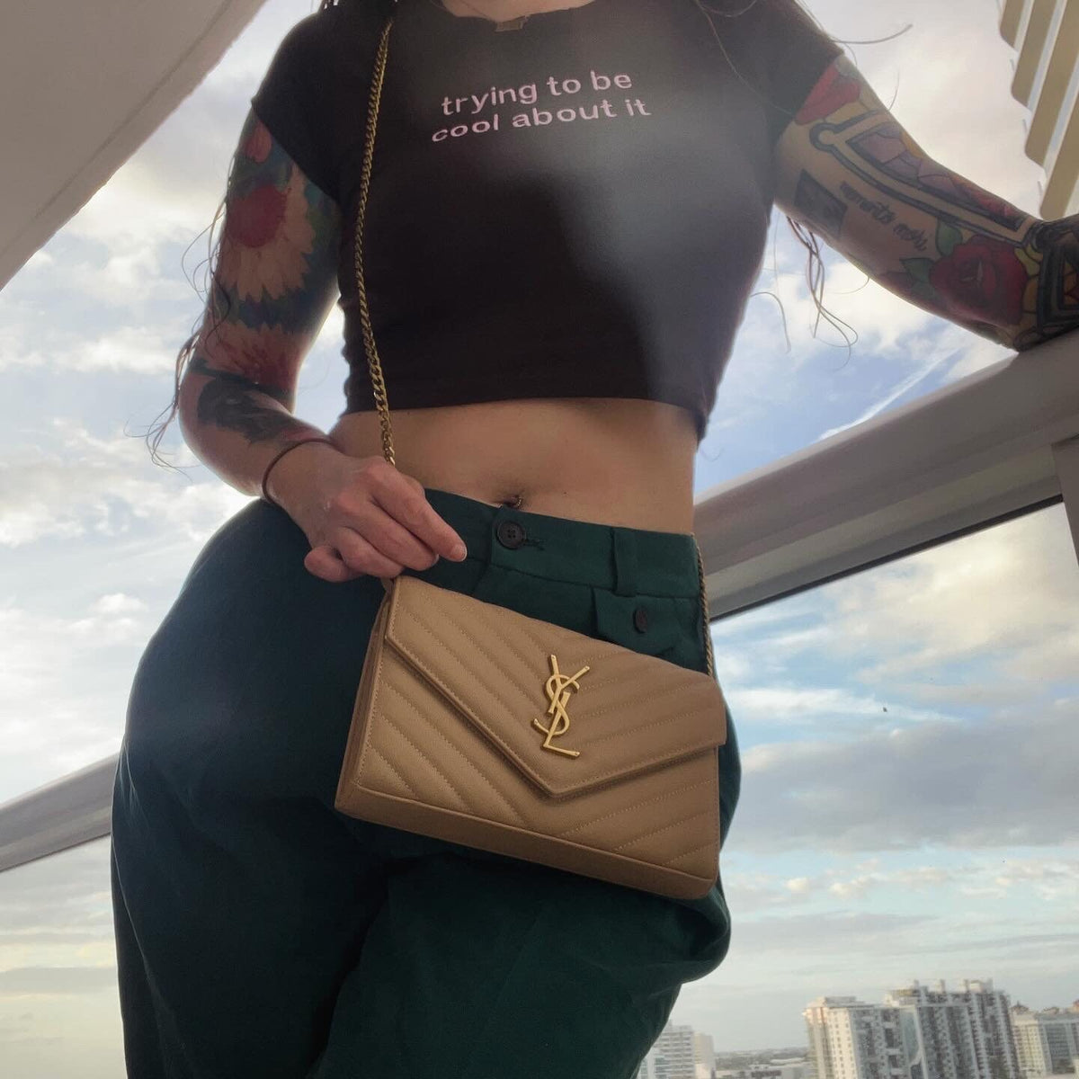 a woman with tattoos holding a tan purse