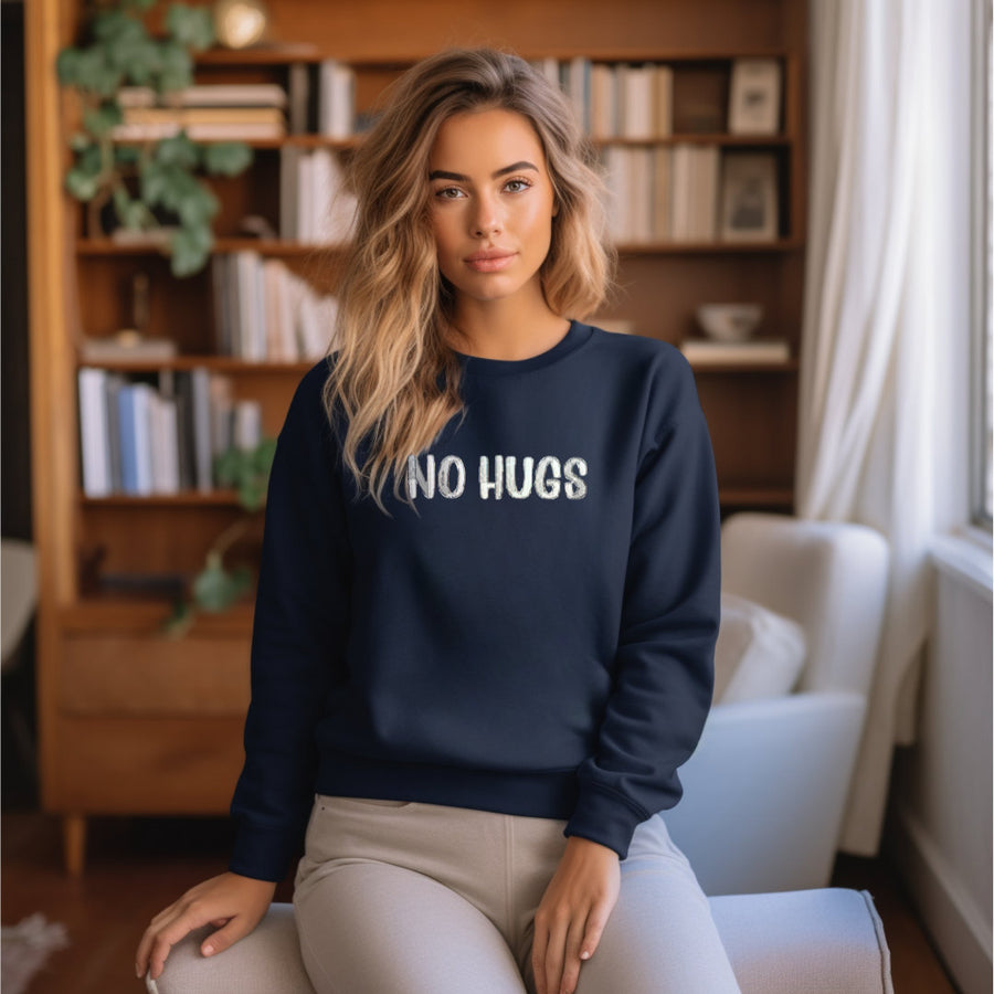 a woman sitting on a chair wearing a sweatshirt that says no hugs