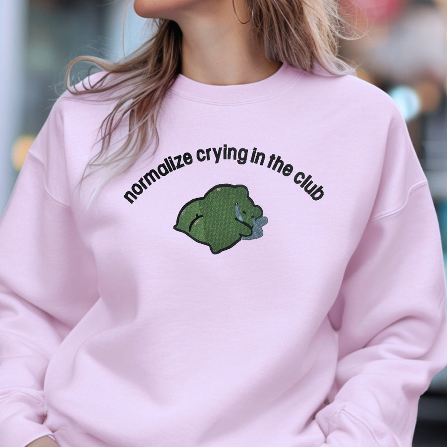 a woman wearing a pink sweatshirt with a green bear on it