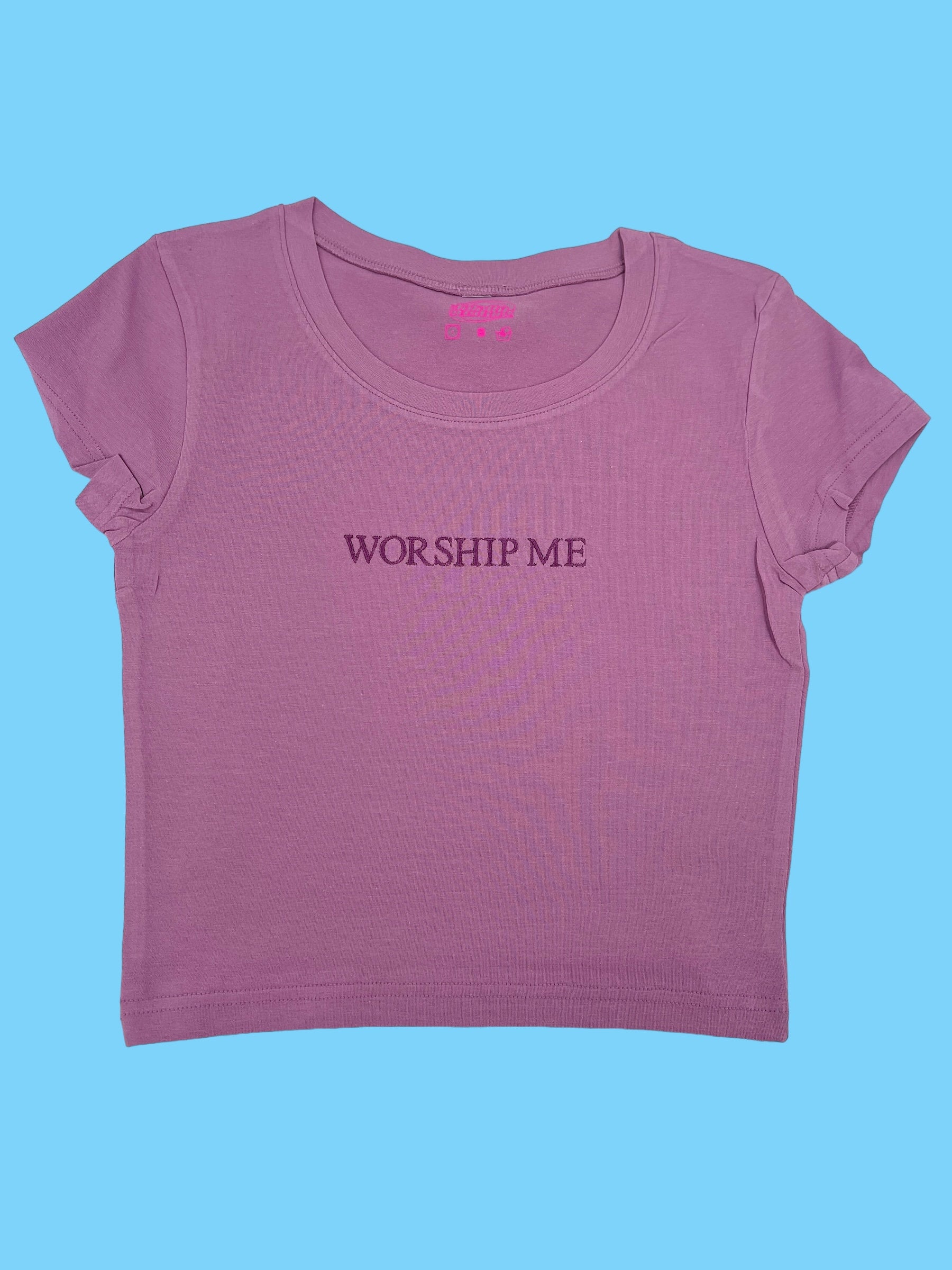 a pink shirt that says worship me on it