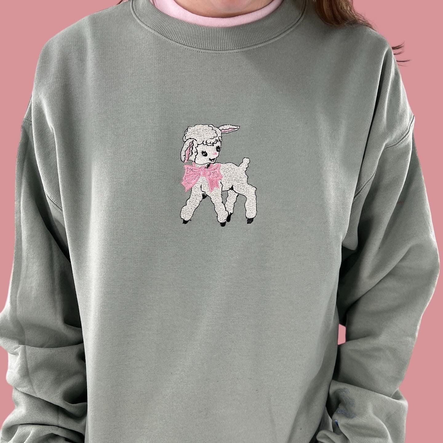 a woman wearing a gray sweatshirt with a pink poodle on it